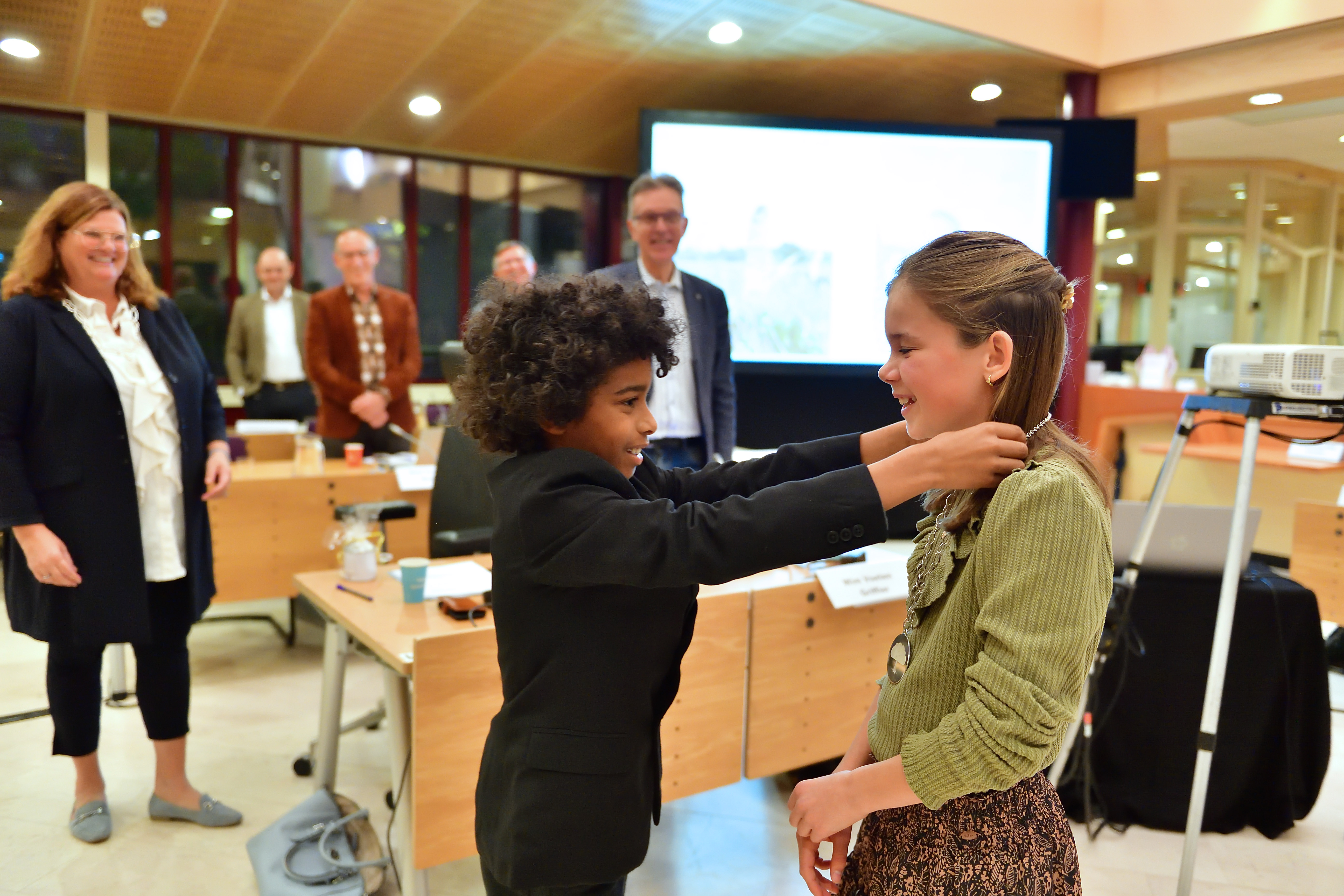 Alain Koroma hangt de ambtsketen om bij de nieuwe jeugdburgemeester Vieve van Kuijk